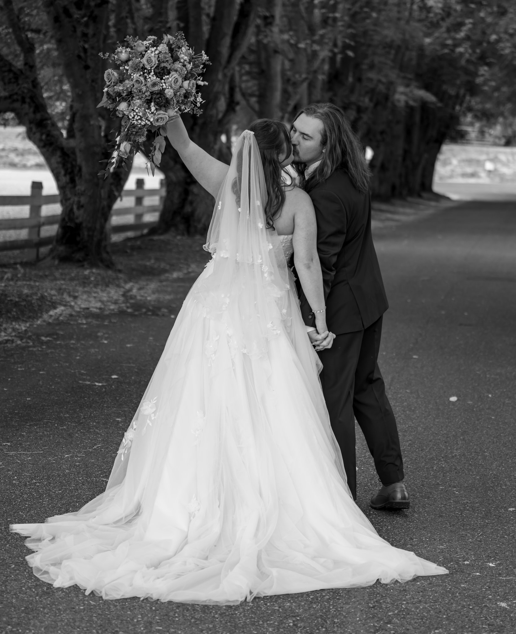 Newlyweds kissing beneath trees