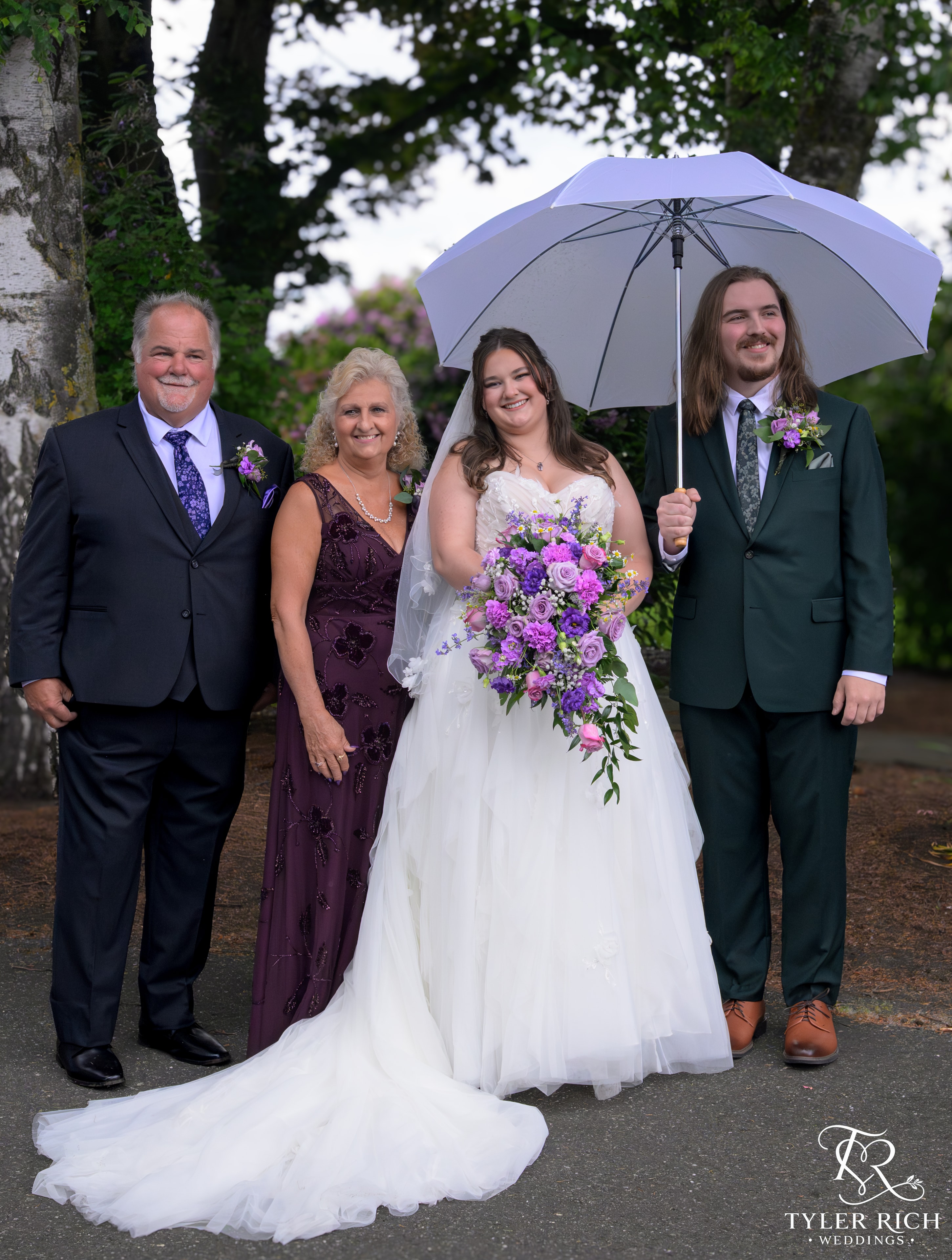 Bride, groom, and family portrait under an umbrella